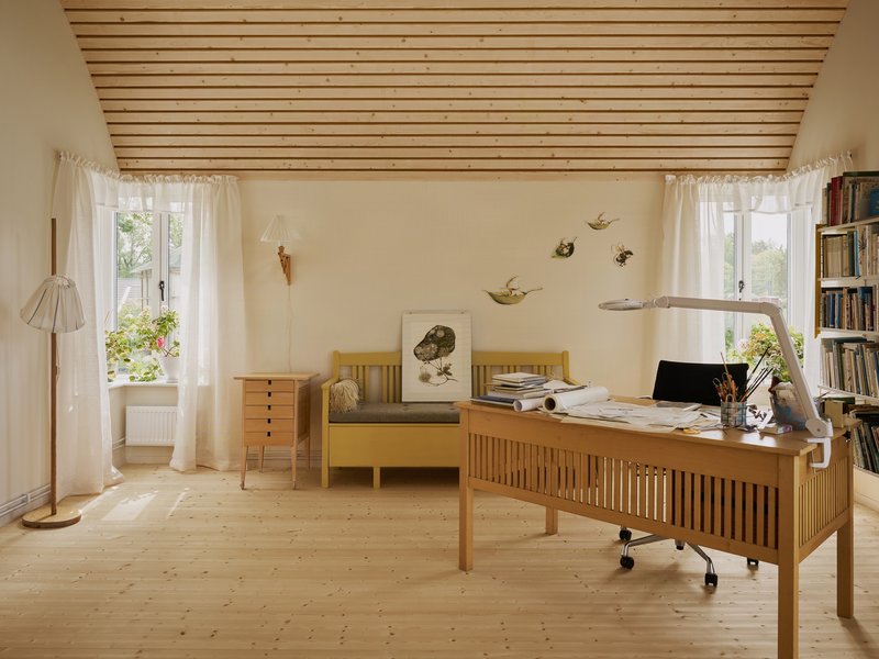Home office with wooden desk and slatted ceiling panel beneath two curtained windows
