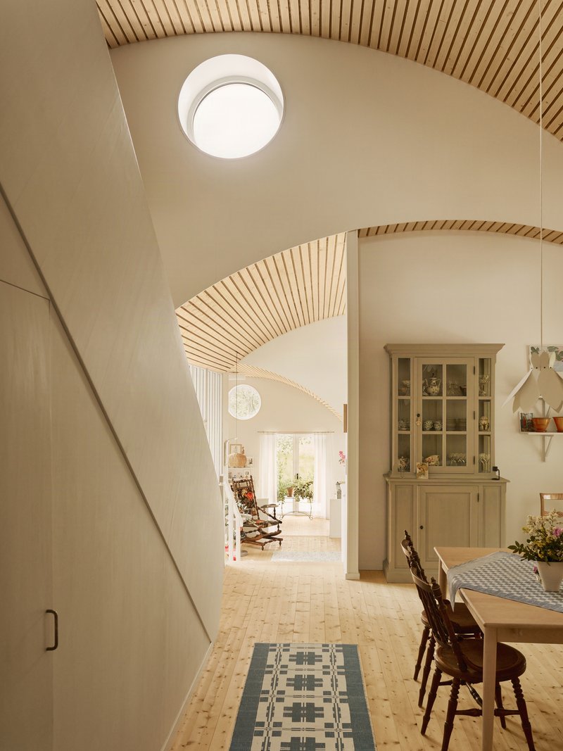 Arched doorway with ribbed wooden ceiling detail leading through dining space to rocking chair