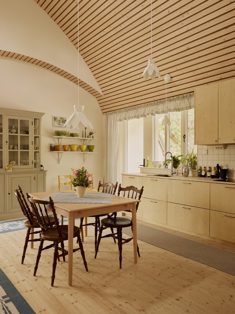 Kitchen and dining area with vaulted wood ceiling and patterned runner on pine flooring