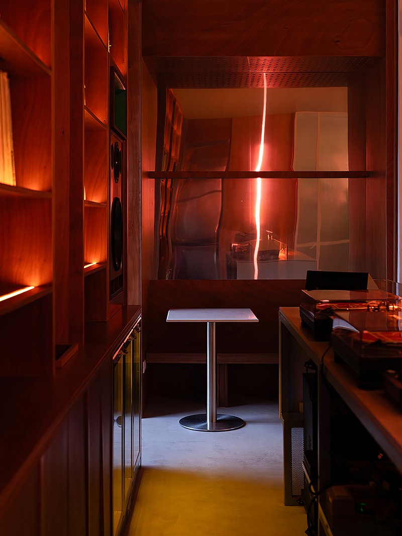 Interior booth with square table reflecting orange sunset light through glass partitions