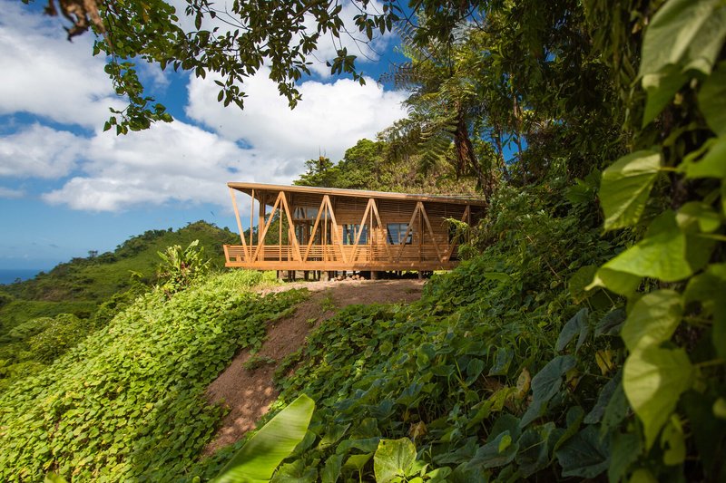 The raised timber structure on a mountainside surrounded by dense tropical vegetation and clouds
