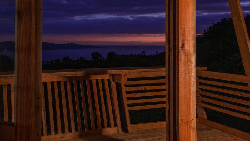 Timber deck with horizontal slatted railing overlooking forested mountains at dusk