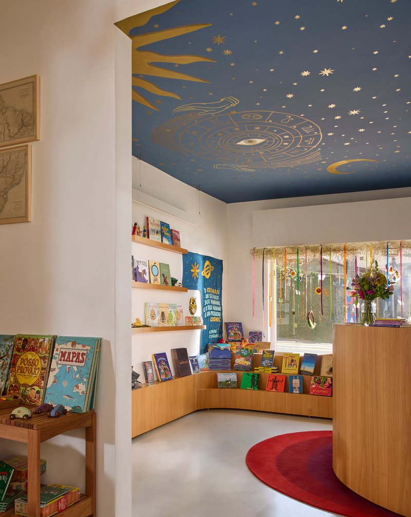 Curved timber display shelving beneath hand-painted celestial ceiling mural with sun, moon, and stars in blue and gold