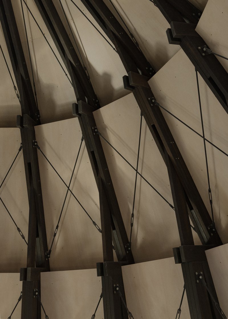 Close-up of the steel beam connections with black metal plates and diagonal cable bracing