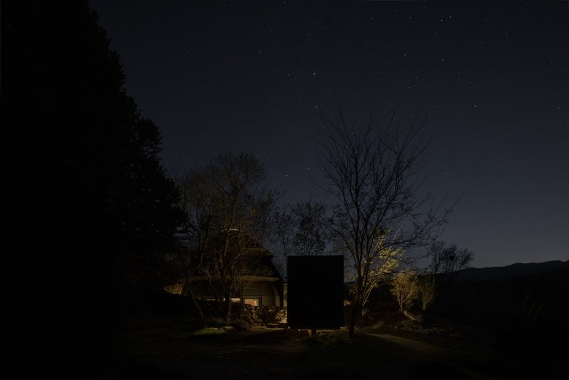 Night view of illuminated dome and timber box volumes under a star-filled sky