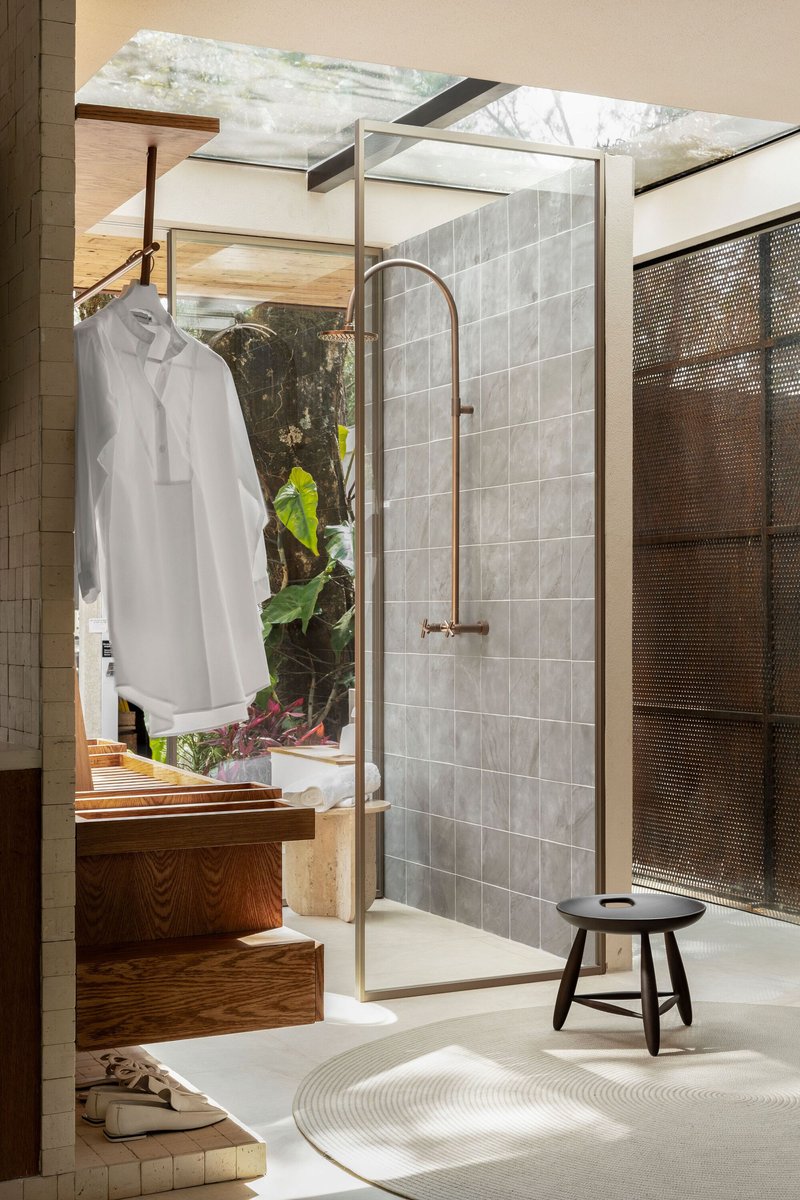 Bathroom with glass-enclosed shower and white tiled wall opening to a planted courtyard