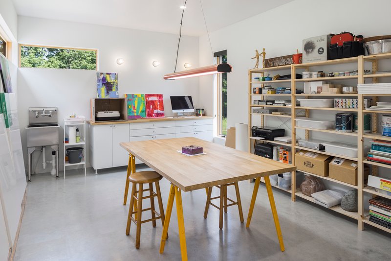 Workshop space with open shelving, work table on yellow trestle legs, and polished concrete floor