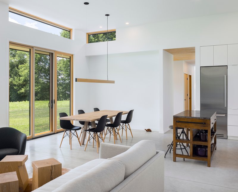 Open-plan living and dining space with clerestory windows overlooking a green meadow