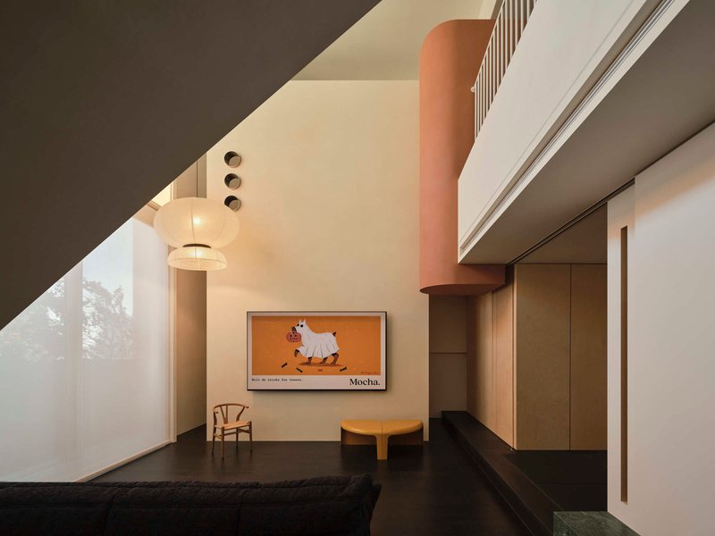 Angled ceiling plane meeting white walls beneath mezzanine level with pendant sphere light illuminating at dusk