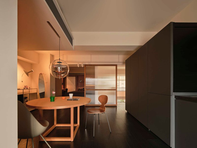 Dining area with timber table and globe pendant light looking through sliding screen toward outdoor balcony