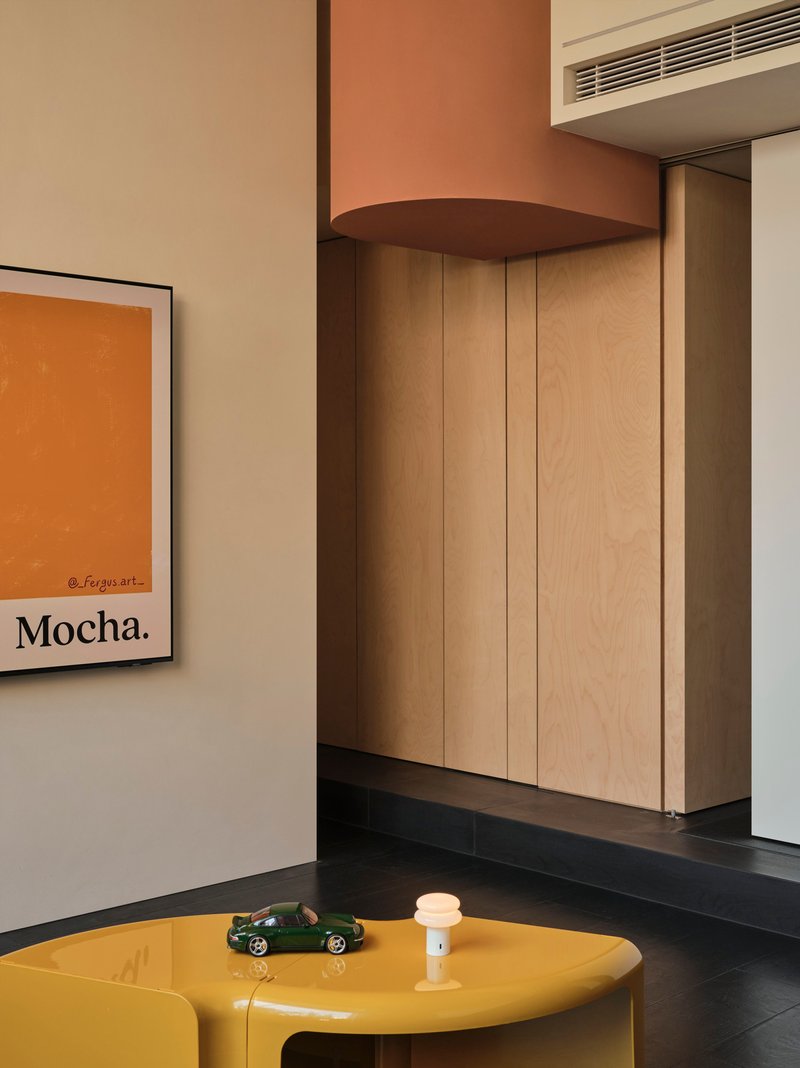 Light wood storage wall with rounded soffit beneath a recessed linear air vent