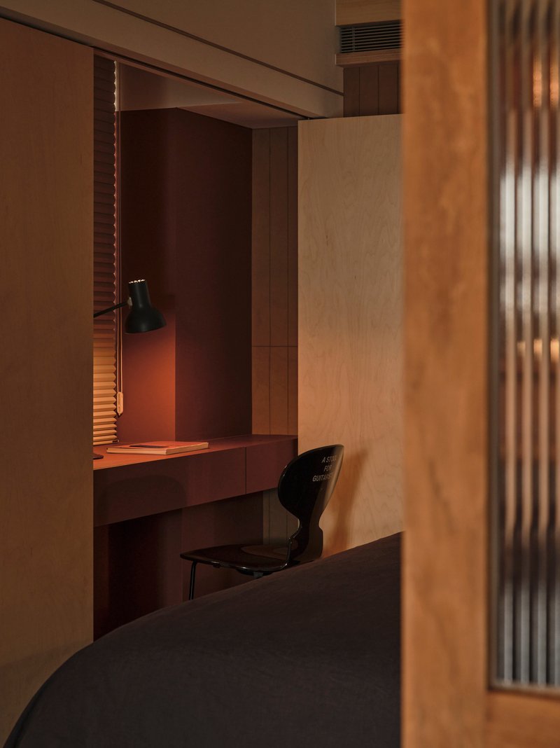 Built-in desk alcove with timber paneling and a black pendant lamp casting warm light