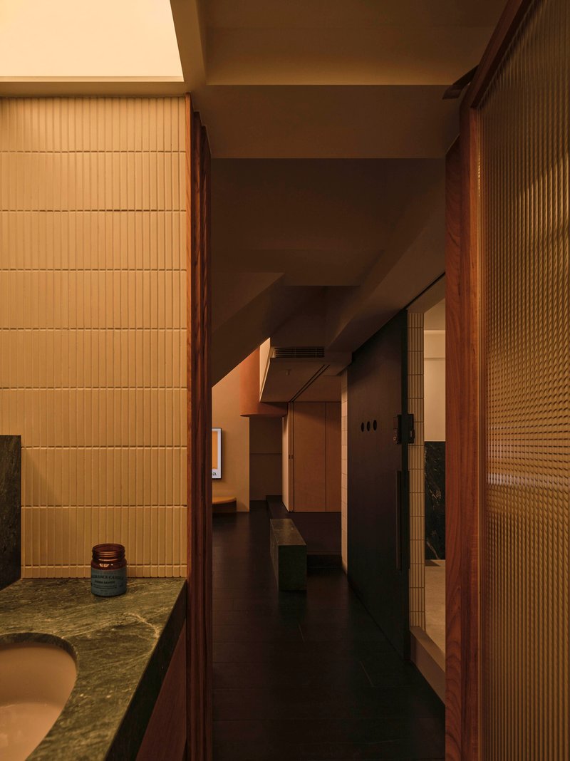 Corridor with ribbed glass panels and horizontal tile wall bathed in warm ambient light