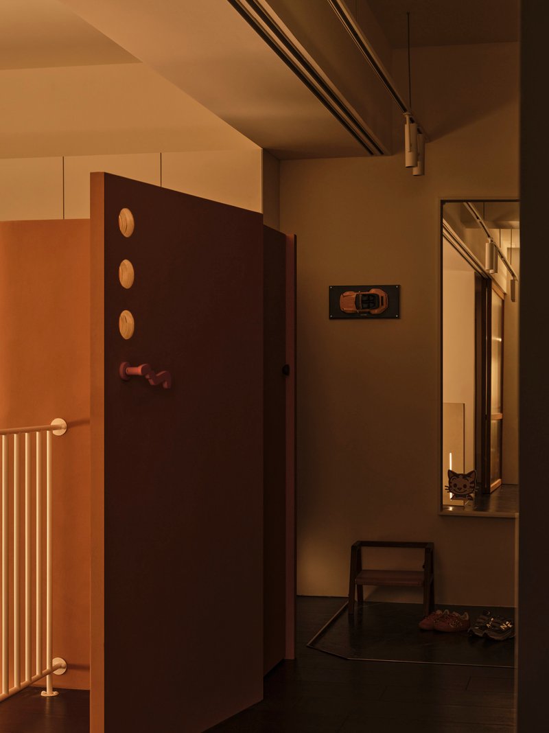 Interior hallway corner showing dark wall with circular openings and a tall mirror reflecting the passage