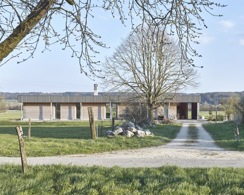 Linear single-story residence with vertical timber sunshades above concrete block walls framed by bare winter trees