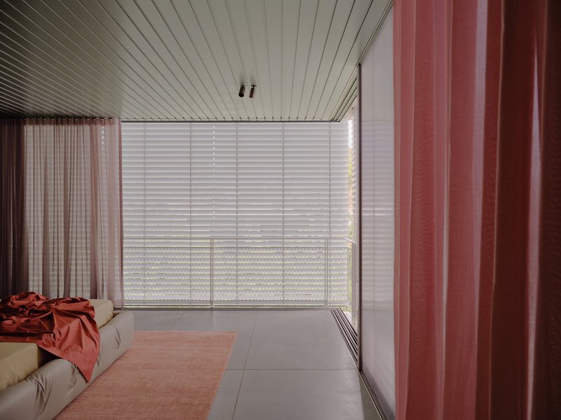 Living room with slatted ceiling, frosted glass privacy screen, and pink curtain panels