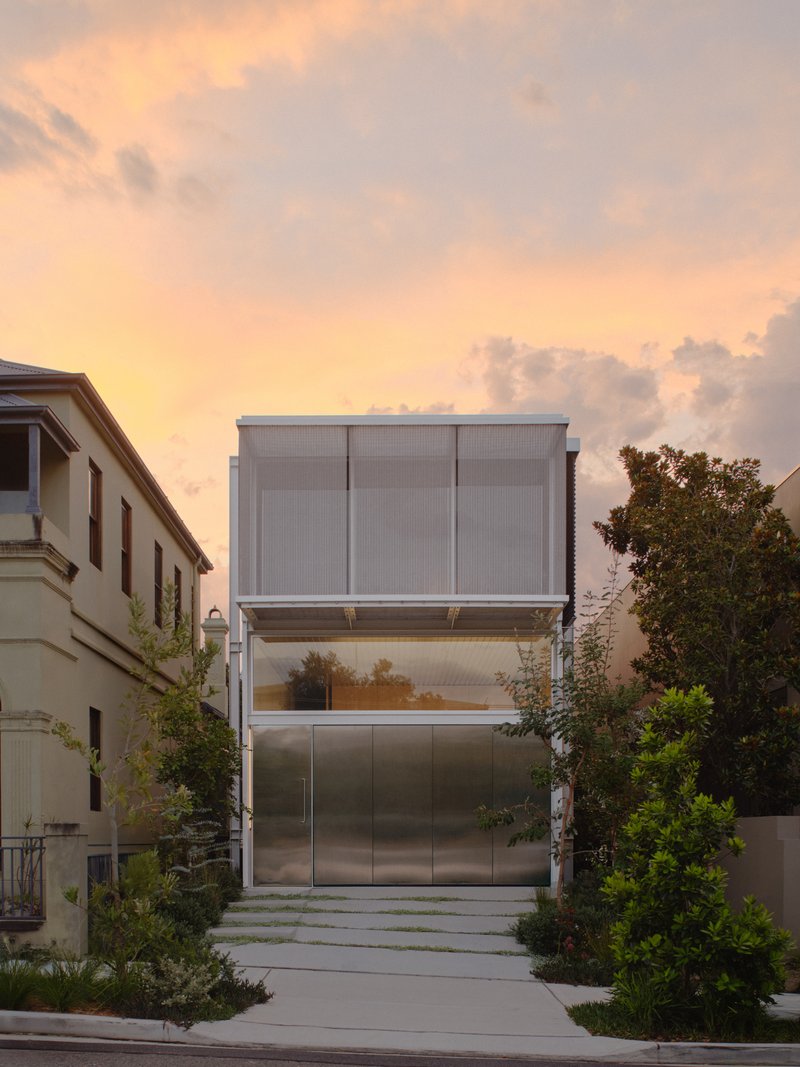 Street view of stacked metal and glass facade with translucent panels at sunset