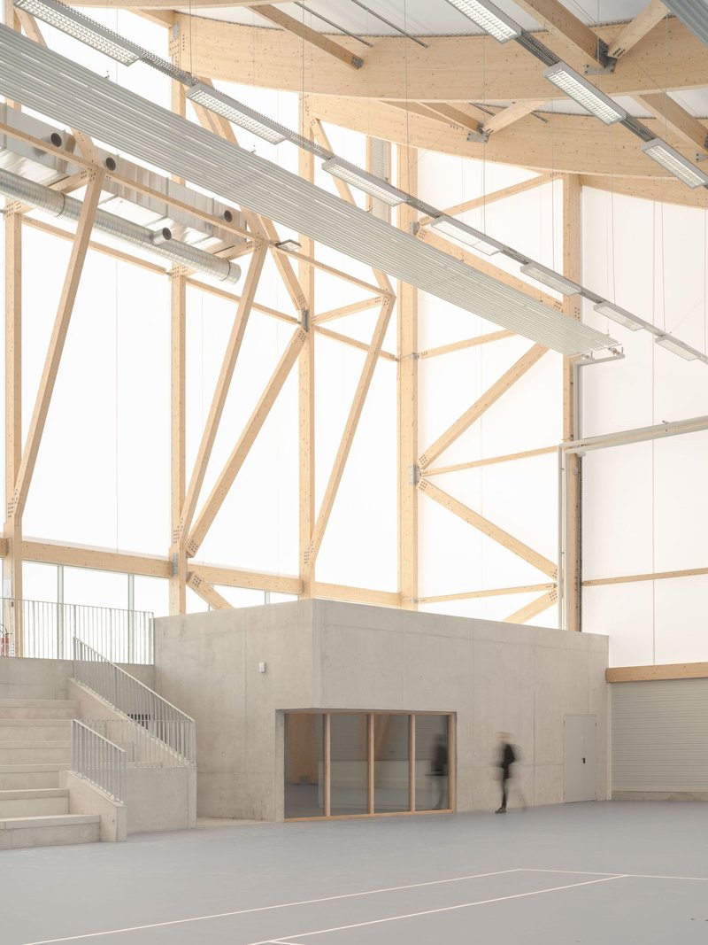 Concrete service box with stairs and timber structural frame against translucent wall panels and moving figures