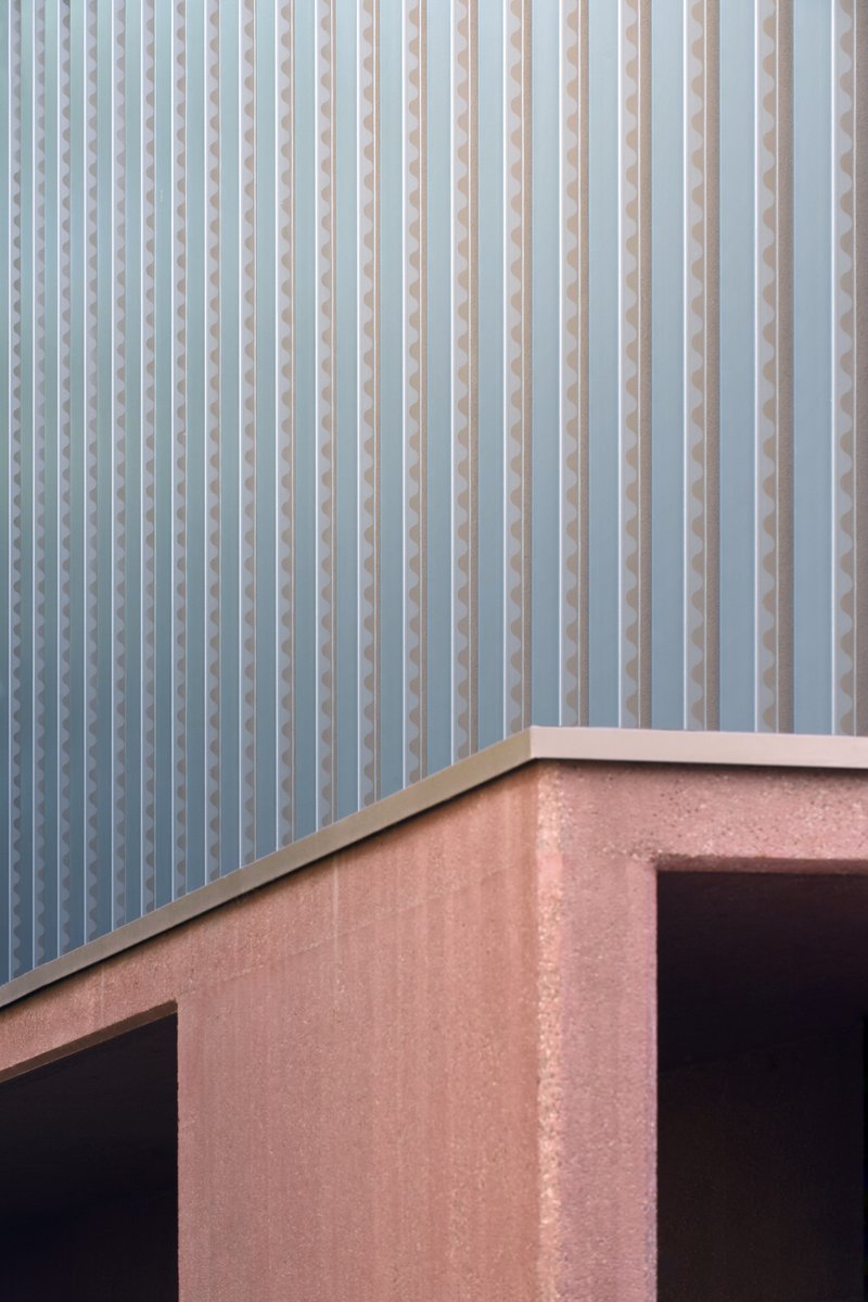 Close-up of pink stucco parapet meeting vertical white metal screen on upper level