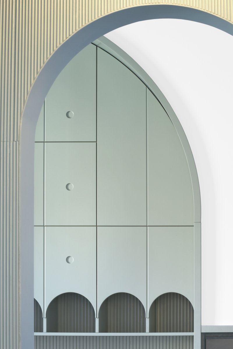 Close-up of arched cabinet panels in pale green with circular pulls and arched cutouts at base