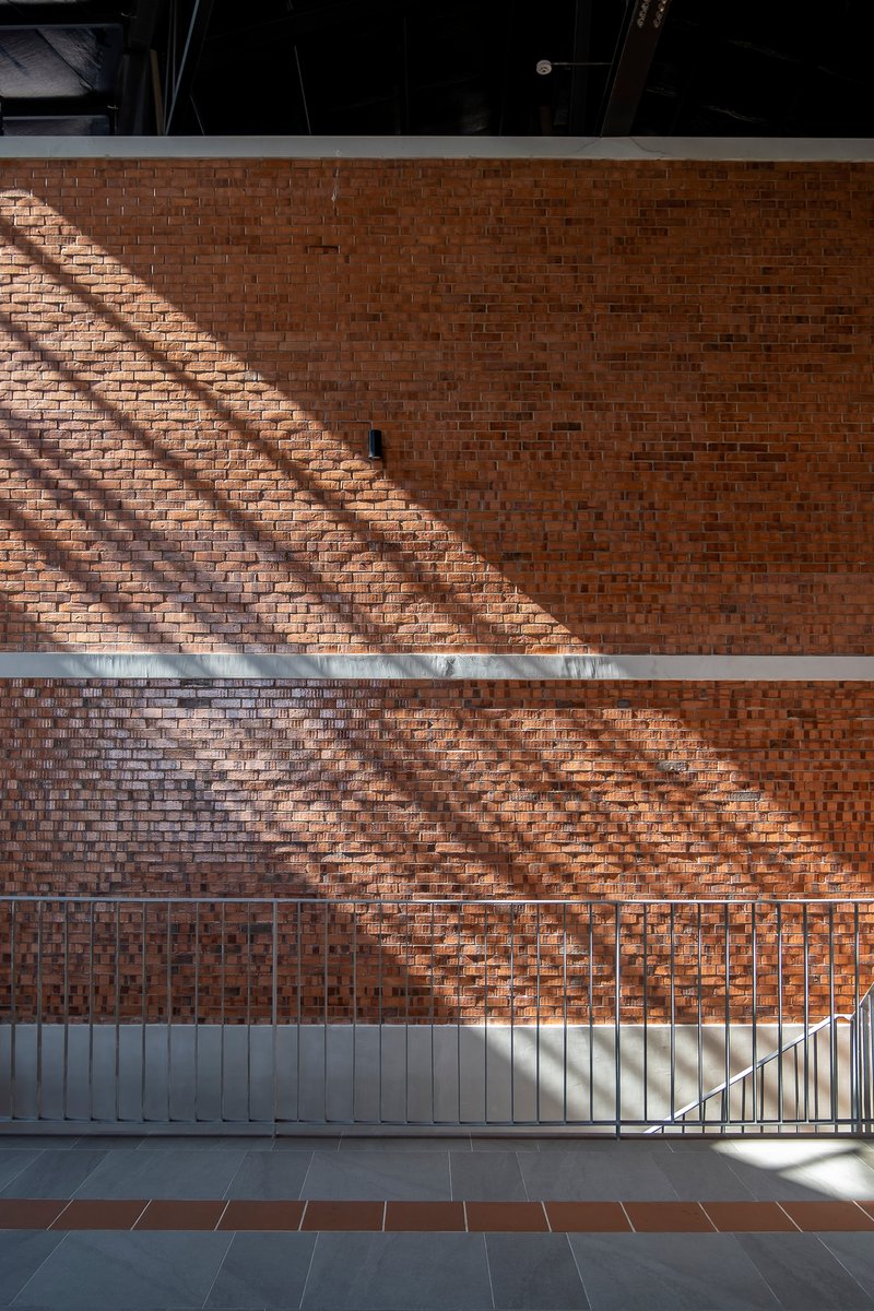 Perforated brick wall with diagonal shadow patterns cast from structural elements above