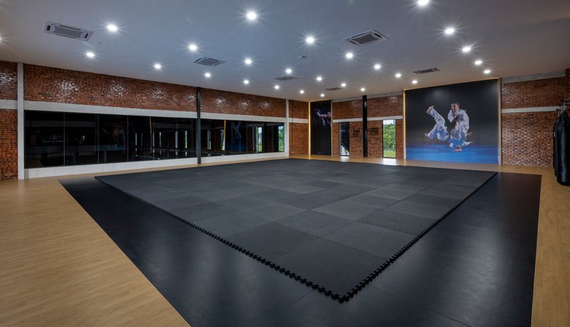 Interior training hall with black mat flooring and perforated brick walls under recessed ceiling lights
