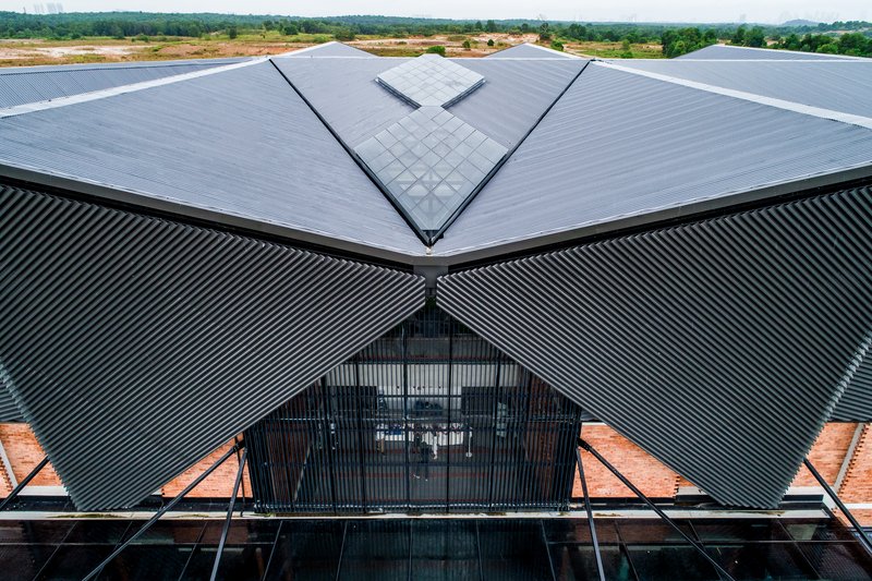 Aerial view of the triangular corrugated metal roof and central glazed gable in open landscape
