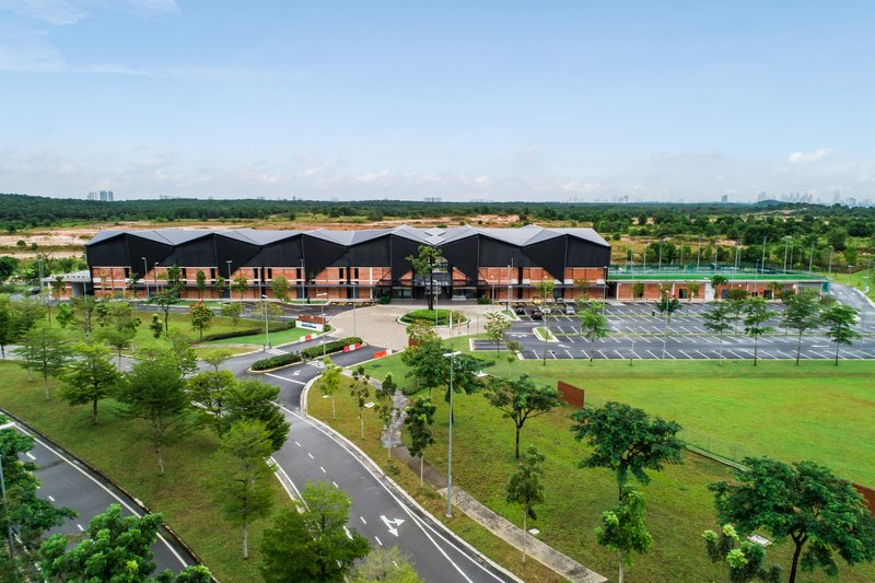 Aerial view of the multi-gabled complex with parking lot and tree-lined roadways in open landscape