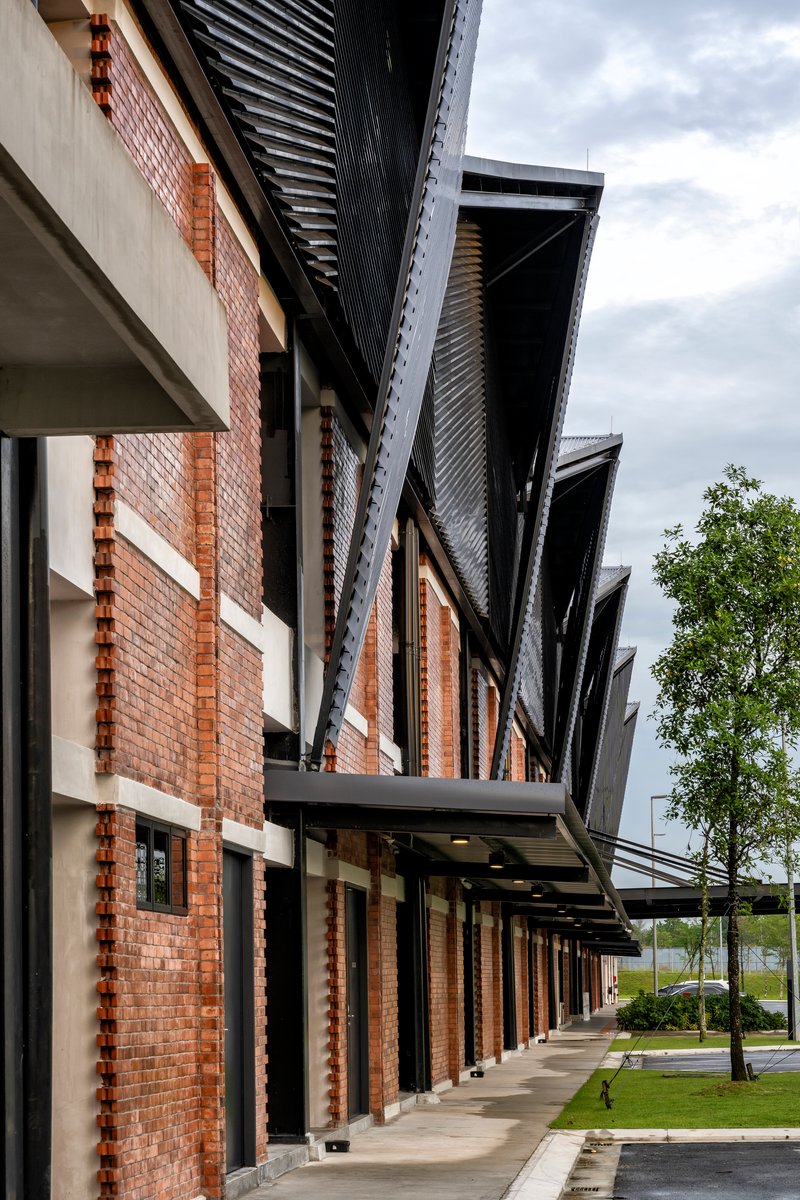 Covered walkway with brick facade and corrugated metal roof eaves under cloudy skies