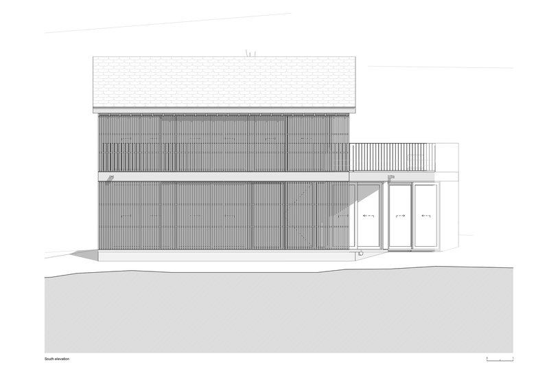 South elevation drawing showing the corrugated siding facade with upper balcony and recessed glazed entry doors