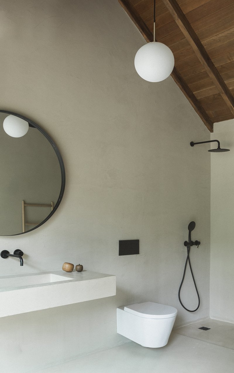 Bathroom with vaulted timber ceiling, wall-hung toilet, and black shower fixtures with globe pendant