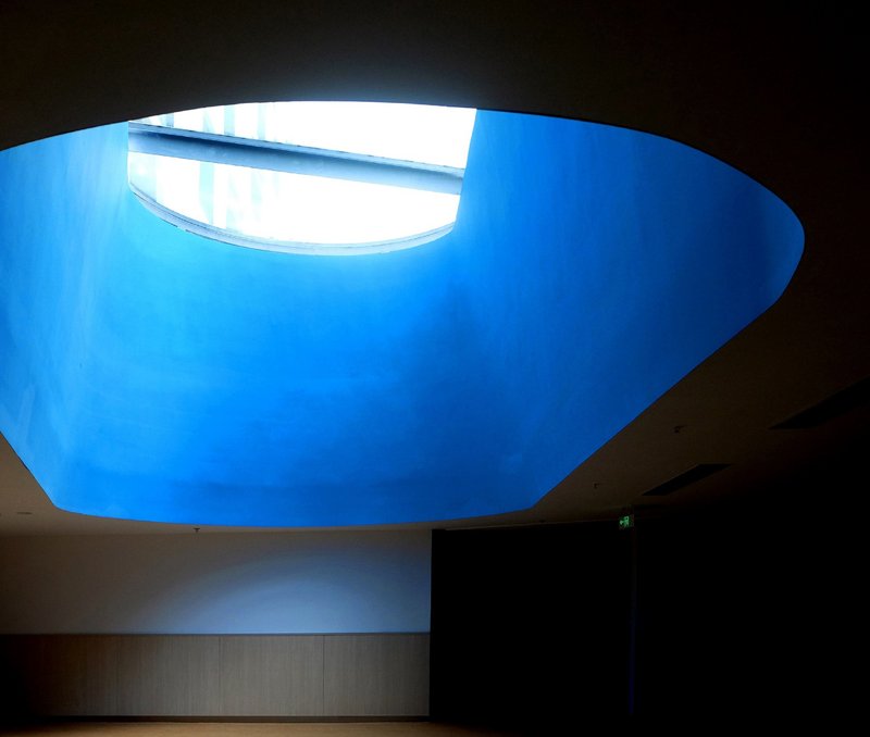 Oval skylight opening with blue sky illuminating the curved interior ceiling from above