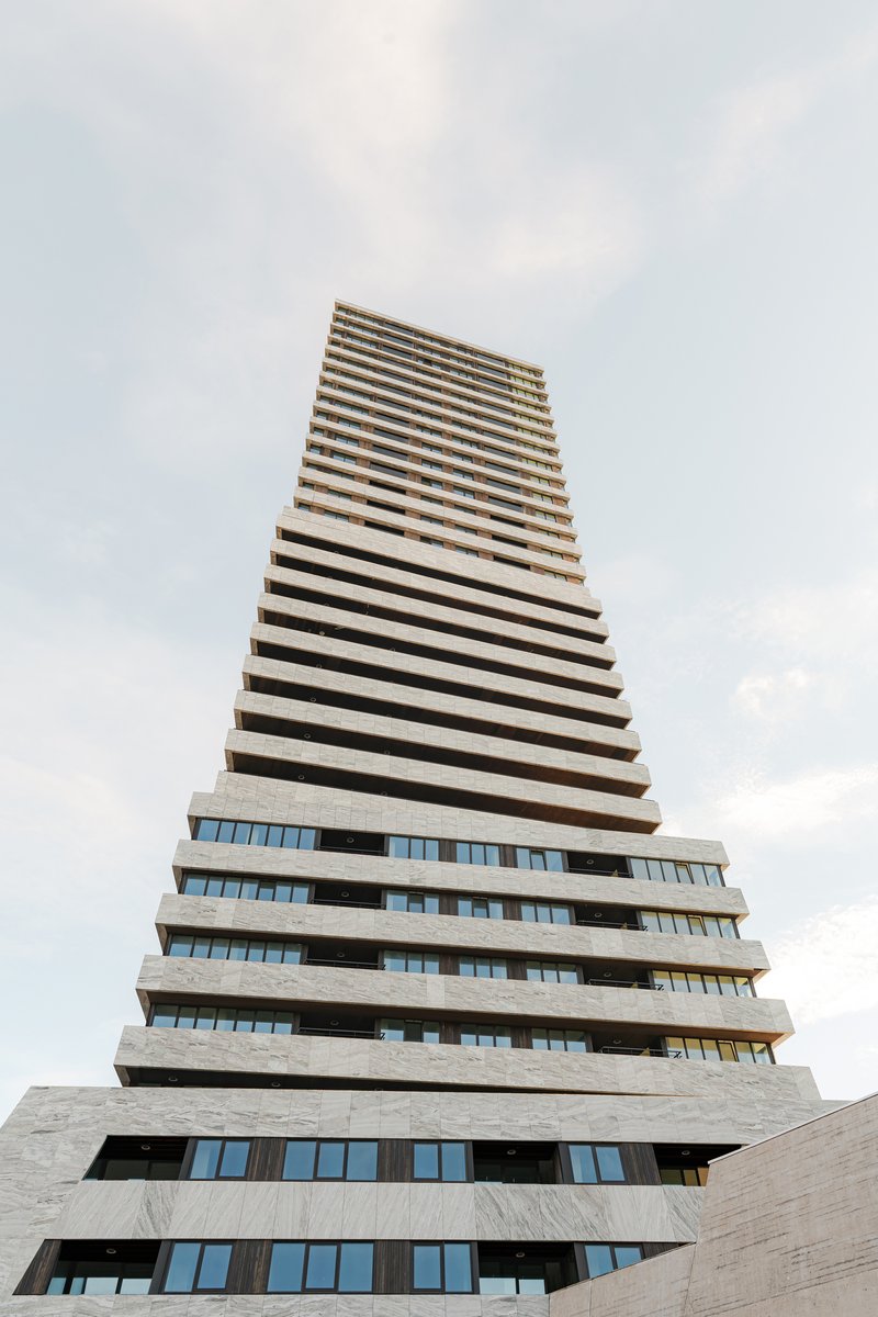 Upward view of the stepped concrete balconies forming a tapering tower against cloudy skies