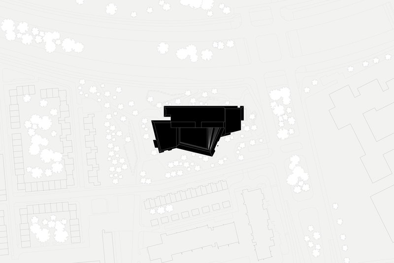 Site plan drawing showing the angular building footprint surrounded by trees and neighboring structures