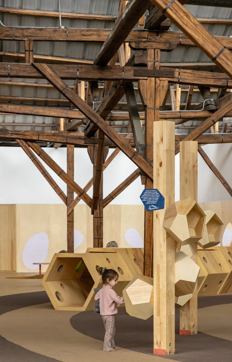 Timber post beneath diagonal bracing with a child exploring hexagonal plywood play modules