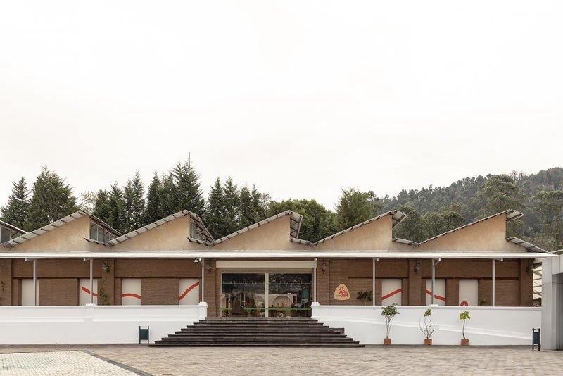 Front facade with repeating sawtooth roofline and central entrance steps leading to a paved plaza