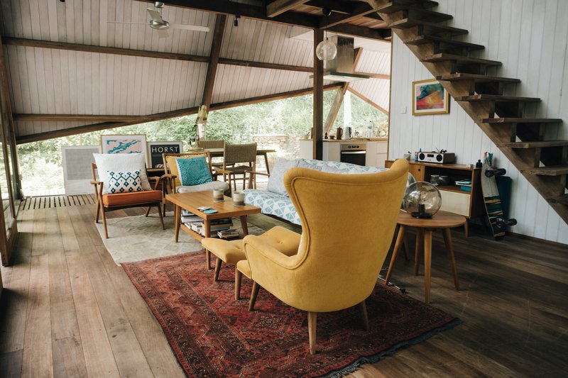 Living area with timber flooring, patterned rug and open stair beneath diagonal bracing