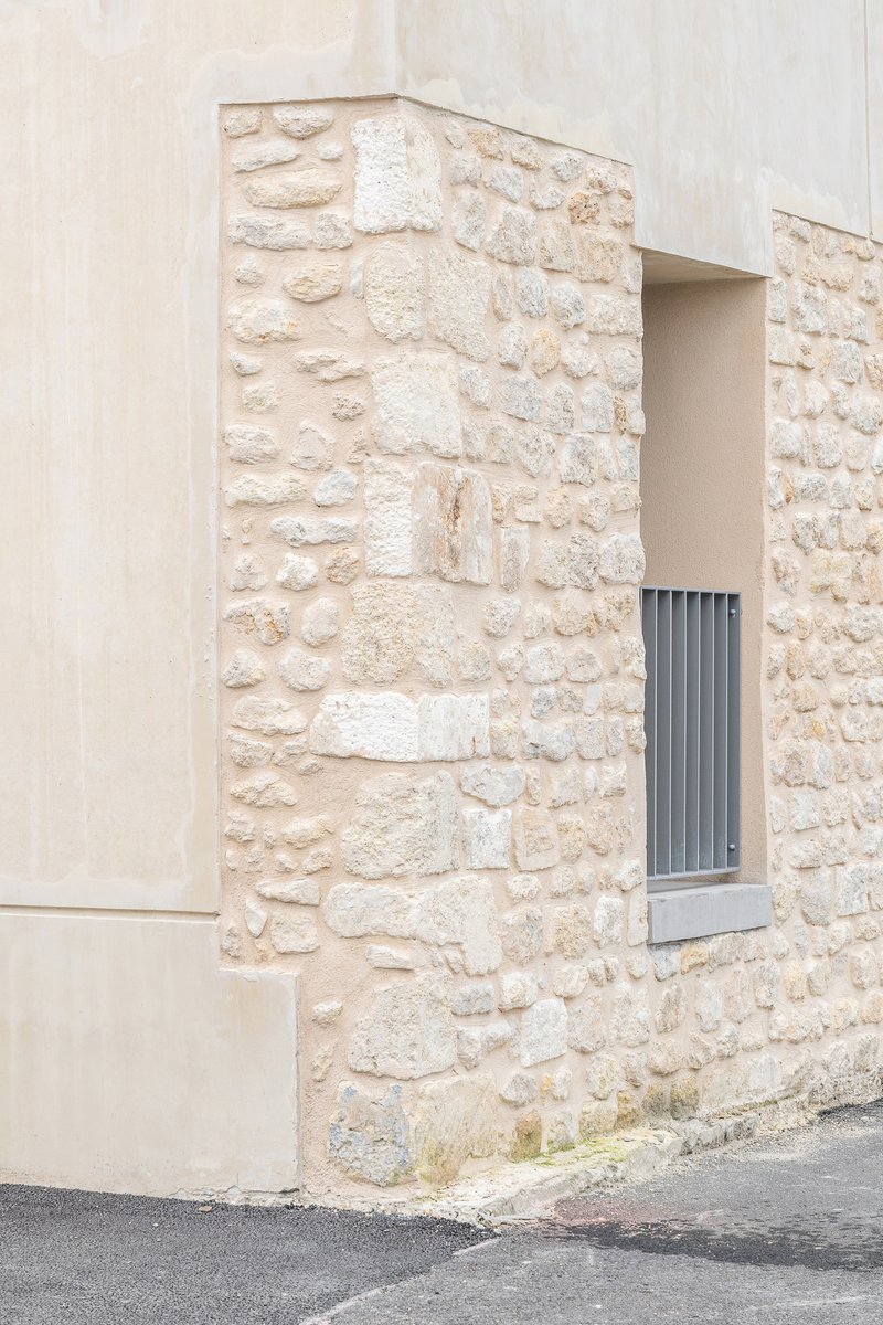 Close-up of the limestone wall corner with a small recessed window and smooth plaster edge