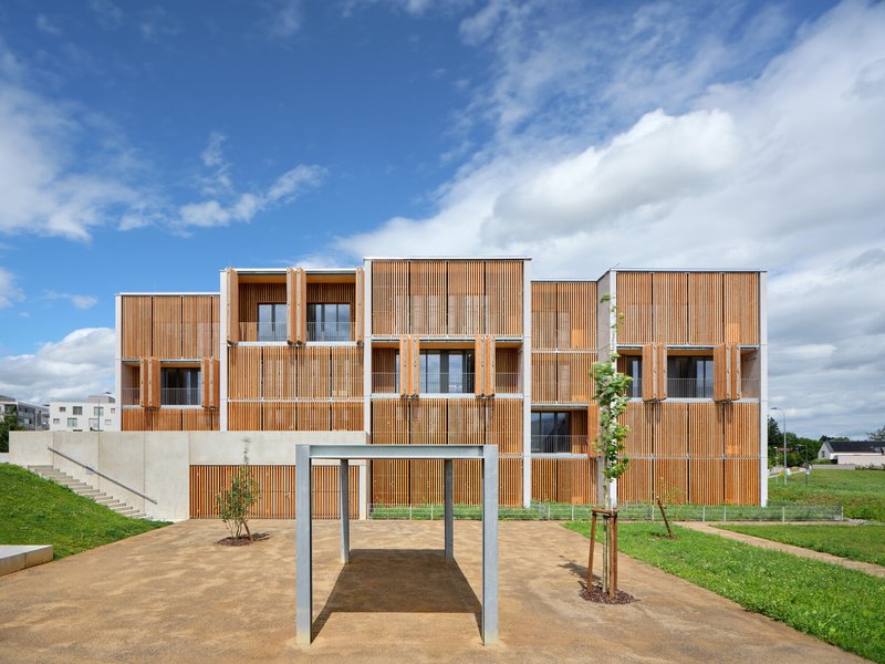 Residential facade showing stacked volumes with vertical timber screening and recessed balconies