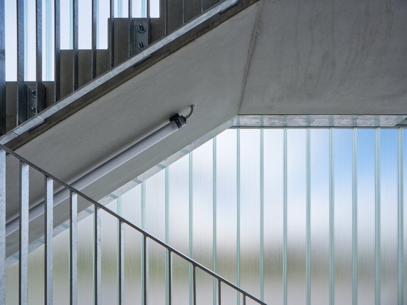 Stairwell with translucent corrugated paneling and concrete soffit viewed from below