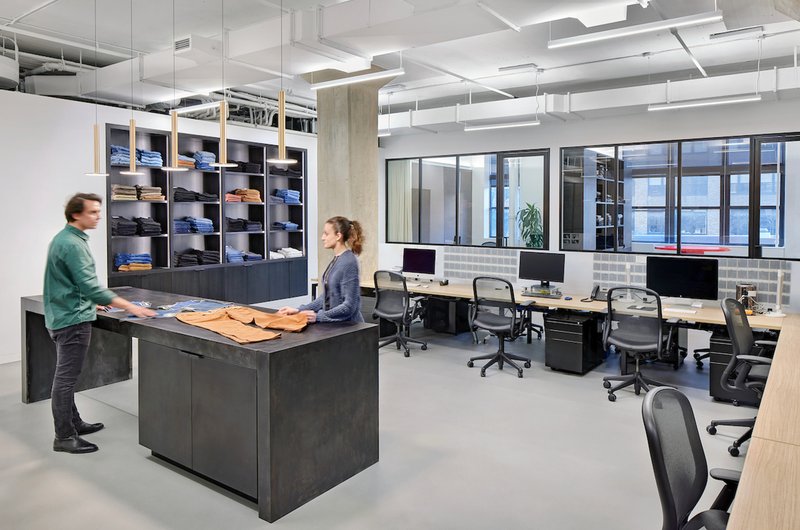Workspace with dark millwork storage wall and two people standing at a central work counter