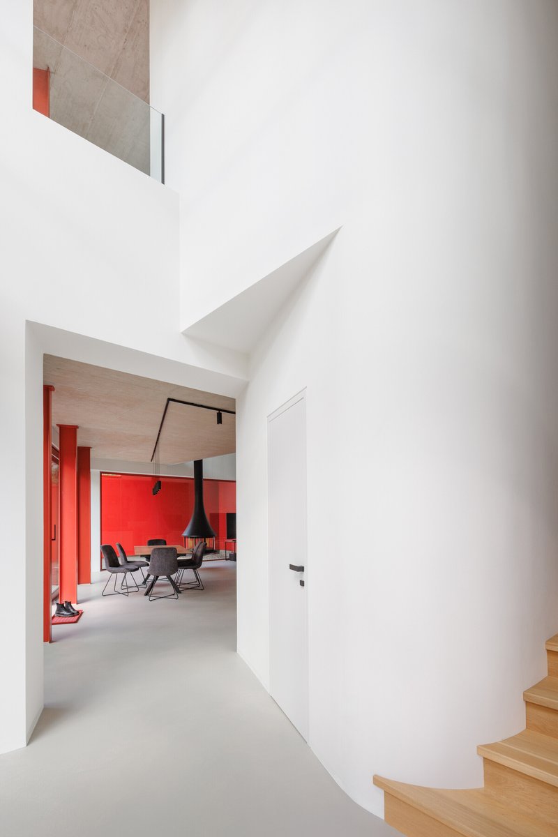 White corridor with curved cylindrical wall leading toward a room with red accent columns