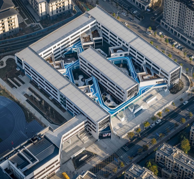 Aerial view of perimeter block building with blue interior courtyard pathways in morning light