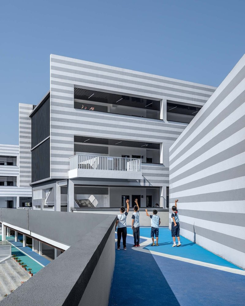 Rooftop playground with blue safety surfacing and students gathering under clear blue sky