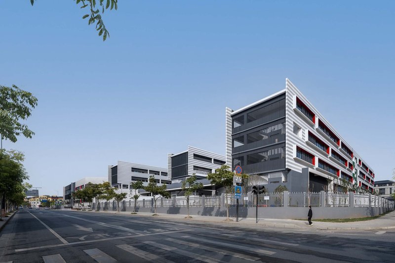 Corner view from the street showing layered white and dark grey facade with pedestrian passing by