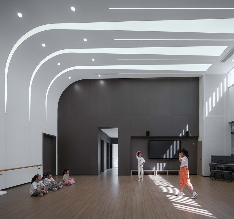 Multi-purpose hall with arched white ceiling ribs and timber flooring lit by striped afternoon sunlight
