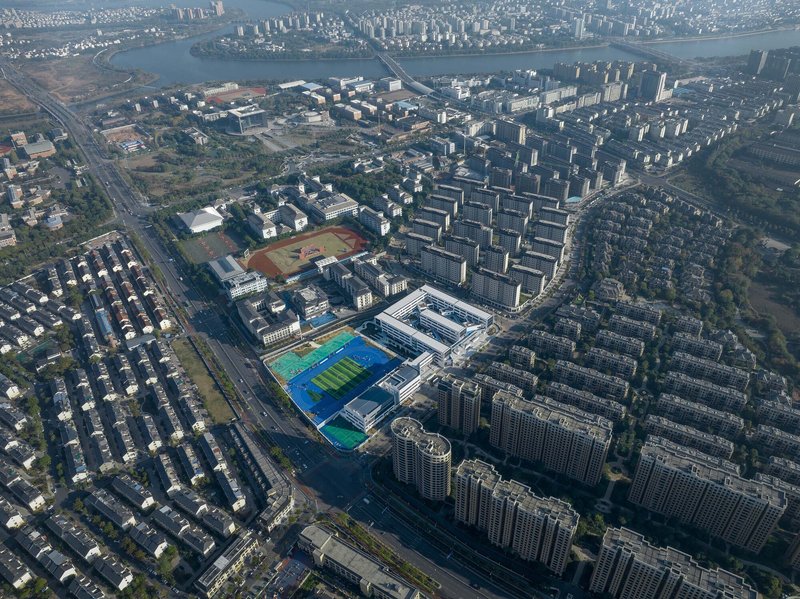 Aerial view of the school campus surrounded by residential towers and waterways in morning light