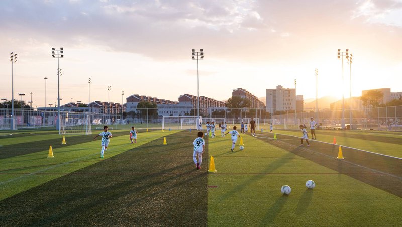 Youth soccer practice on artificial turf fields with yellow training cones at golden hour