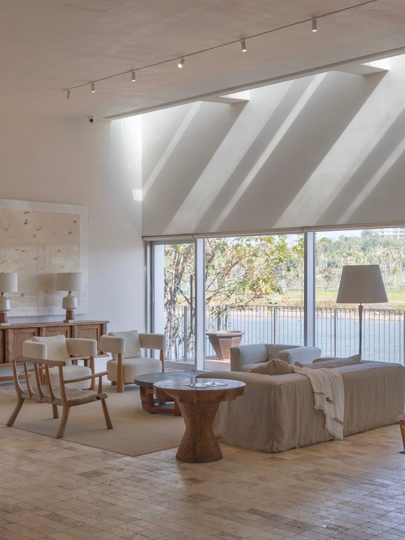 Living room with angled white fabric ceiling baffles and windows framing trees along the waterfront