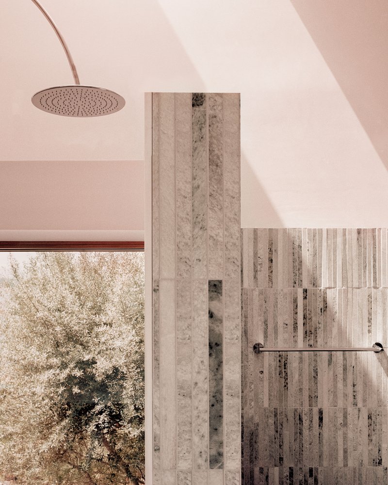 Bathroom with vertical stone tile wall and curved plaster ceiling beneath a skylight